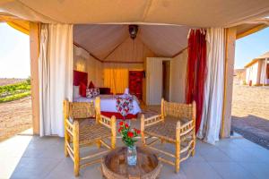a tent with a bed and chairs and a table at Agafay Pearl Camp Marrakech in Marrakesh
