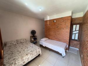 a bedroom with two beds and a brick wall at HOSTEL NATIVOS in Linhares