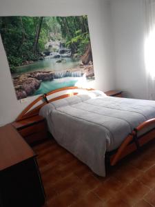 a bedroom with a bed with a painting of a river at Entre els pirineus in La Seu d'Urgell