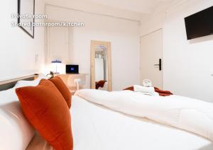 a white bedroom with two beds with orange pillows at weroomies - Pons Icar H1 in Tarragona