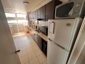 a kitchen with a white refrigerator with a microwave on top at Habitaciones con C in Concepción