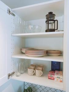 a white pantry with plates and dishes on shelves at Relax Inn Otepää Apartment in Otepää +8 photos