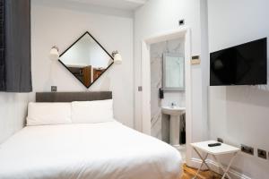 a bedroom with a white bed and a mirror at MSK Hotel 82 in London