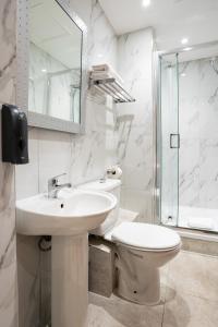 a white bathroom with a toilet and a sink at MSK Hotel 82 in London