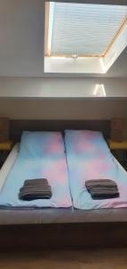 two towels sitting on a bed under a window at Къща за гости ОЗИ 3 in Ovchartsi