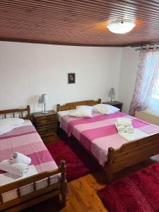 a bedroom with two beds with pink and white sheets at Lithos Home in Panagia