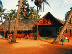 a hut with palm trees in front of it at Sunrich Beach Resort in Ilandaiyadi