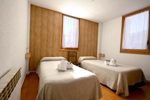 a room with two beds and two windows at Habitacions La Coma de Taüll in Taüll