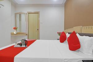 a bedroom with a white bed with red pillows at Hotel O Padmini Near Lakdikapool Metro Station in Hyderabad
