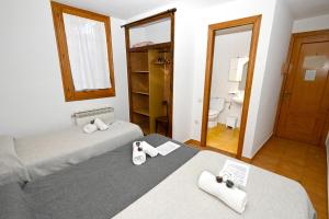 two beds in a room with a bathroom at Habitacions La Coma de Taüll in Taüll