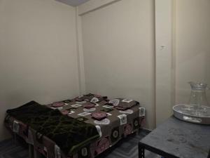 a small bed in a room with a table at Yamuna Bank Inn in Prayagraj