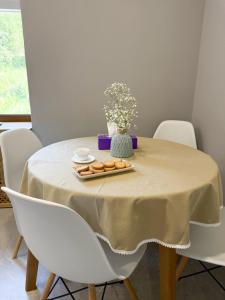 a table with white chairs and a table with food on it at Hygge Apartment in Mizhhirya