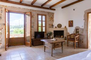 a living room with a fireplace and a television at Tzokeika Traditional Settlement in Riglia