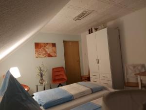 a bedroom with a bed and a cabinet and a chair at Pension Renate Braun in Gamstädt