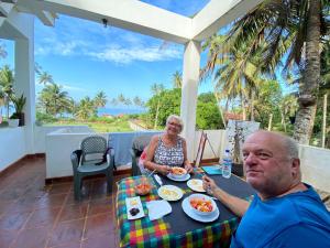 a man and a woman sitting at a table with food at Ayona Beach Villa in Katuneriya