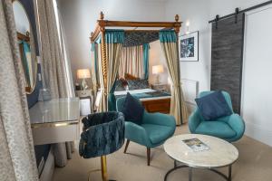 a bedroom with a canopy bed with blue chairs and a table at Herriots Hotel in Skipton