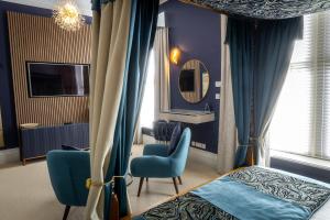 a bedroom with a bed and two chairs and a mirror at Herriots Hotel in Skipton