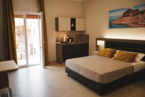 a bedroom with a large bed and a kitchen at YEASY smart rooms Cefalù in Cefalù