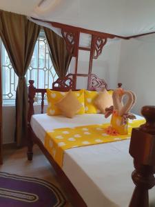 a bedroom with a canopy bed with yellow pillows at White Jaguar House in Bwejuu