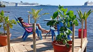 a woman sitting in a chair on a dock with a cruise ship at Hotel Victoria s Beach House in Roatán