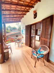 a living room with wicker chairs and a patio at Íkaia Surf House in Ubatuba
