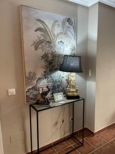 a table with a lamp and a painting on the wall at Parque Vera 5 in Vera