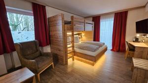 a bedroom with a bunk bed and a chair and a desk at Hotel-Landgasthof Ploss in Schönwald