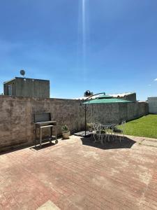 a patio with a table and an umbrella and a grill at Casa de Descanso Don Abel in Chascomús