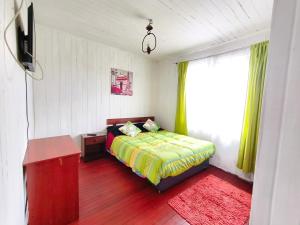 a bedroom with a bed and a window with green curtains at Hospedaje Luna in Valdivia +8 photos