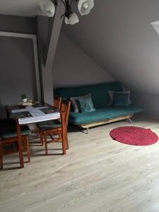 ein Wohnzimmer mit einer grünen Couch und einem Tisch in der Unterkunft Łowicka22 in Piątek + 2 Fotos