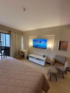 a hotel room with a bed and a couch and a tv at Kubitschek Plaza Hotel - Flat Particular ALM in Brasília