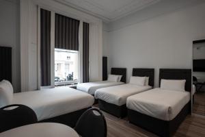 a room with three beds and a window at MSK Elite in London