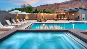 a swimming pool with chairs and tables and a mountain at Gravity Haus Moab in Moab