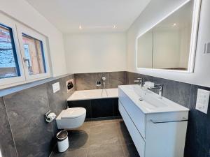 a bathroom with a sink and a toilet and a tub at Brand-New Eiger View 3BR Apartment - Premium Location - Free Parking - Terrace in Grindelwald +25 photos