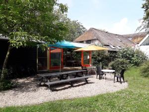 a patio with a table and chairs and an umbrella at Toplocatie voor je workshop! Of grote gezin! Zwembad! in Hurwenen