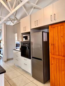 a kitchen with a stainless steel refrigerator and white cabinets at 10 on Sysie in Sedgefield