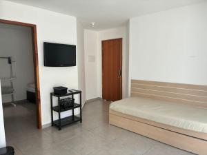 a bedroom with a bed and a flat screen tv at Apartamento do Peró in Cabo Frio