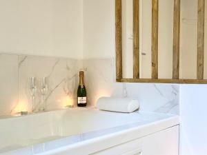 a white kitchen with a bottle of wine and glasses at Le SPA Étoilé - Baignoire Balnéo et Sauna Privatif in Mont-de-Marsan +15 photos