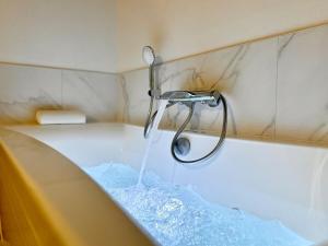a bath tub with a shower with water in it at Le SPA Étoilé - Baignoire Balnéo et Sauna Privatif in Mont-de-Marsan