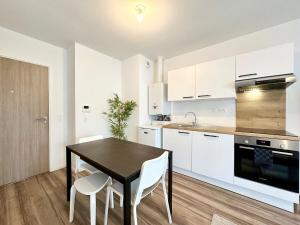 a kitchen with a black table and white cabinets at L'Émeraude - Proche Hôpital - Parking - Clim - Fibre - Terrasse in Mont-de-Marsan