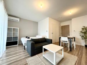 a living room with a couch and a bed and a table at L'Émeraude - Proche Hôpital - Parking - Clim - Fibre - Terrasse in Mont-de-Marsan +9 photos