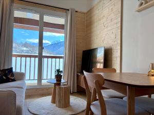 a living room with a table and a large window at Charmant duplex Proche station in Aime-La Plagne