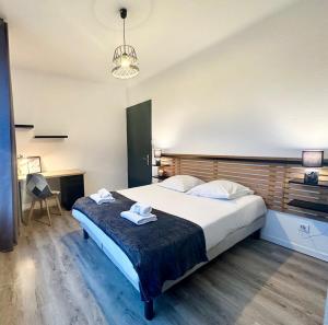 a bedroom with a large bed with two towels on it at L'Évasion - Centre-Ville & Garage Privé in Mont-de-Marsan