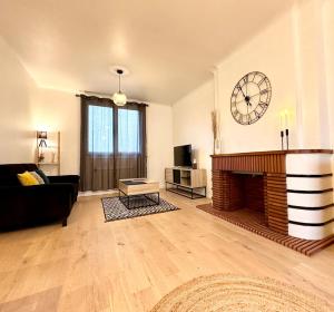 a living room with a fireplace and a clock on the wall at L'Évasion - Centre-Ville & Garage Privé in Mont-de-Marsan