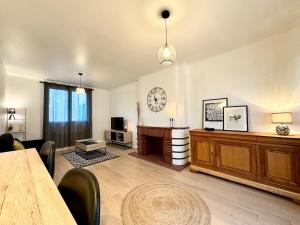 a living room with a table and a clock on the wall at L'Évasion - Centre-Ville & Garage Privé in Mont-de-Marsan +28 photos
