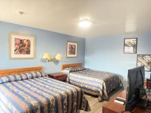 a hotel room with two beds and a flat screen tv at Shady Grove Motel in Ashland