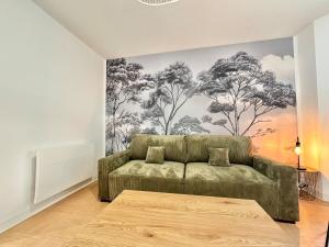 a living room with a couch and a mural of trees at Le Vert D'eau - Raffiné - Central - Balcon in Mont-de-Marsan