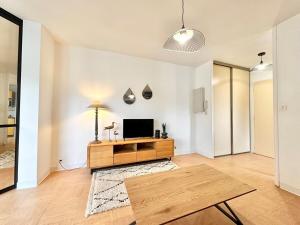 a living room with a tv and a wooden table at Le Vert D'eau - Raffiné - Central - Balcon in Mont-de-Marsan