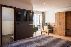 a bedroom with a large black refrigerator and a desk at Alpin Lifestyle Hotel Löwen & Strauss in Oberstdorf