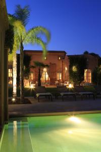 una piscina con panchine di fronte a un edificio di notte di Villa Jannah a Marrakech